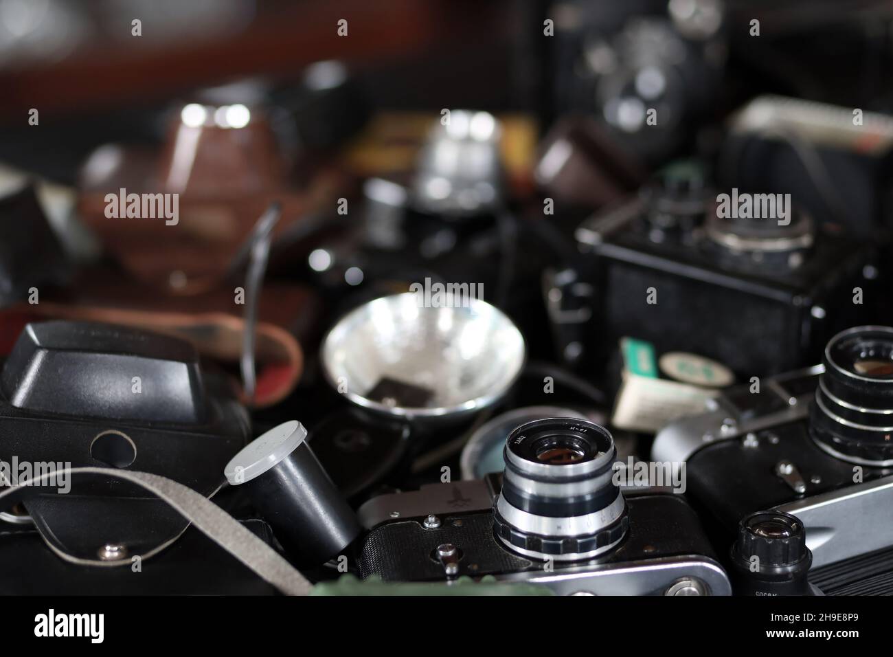 CHARKOV, UKRAINE - 27. APRIL 2021: Filmkameras und eine andere alte Retro-Fotoausrüstung auf schwarzem Holztisch in der Dunkelkammer des Fotografen. Foto Stockfoto