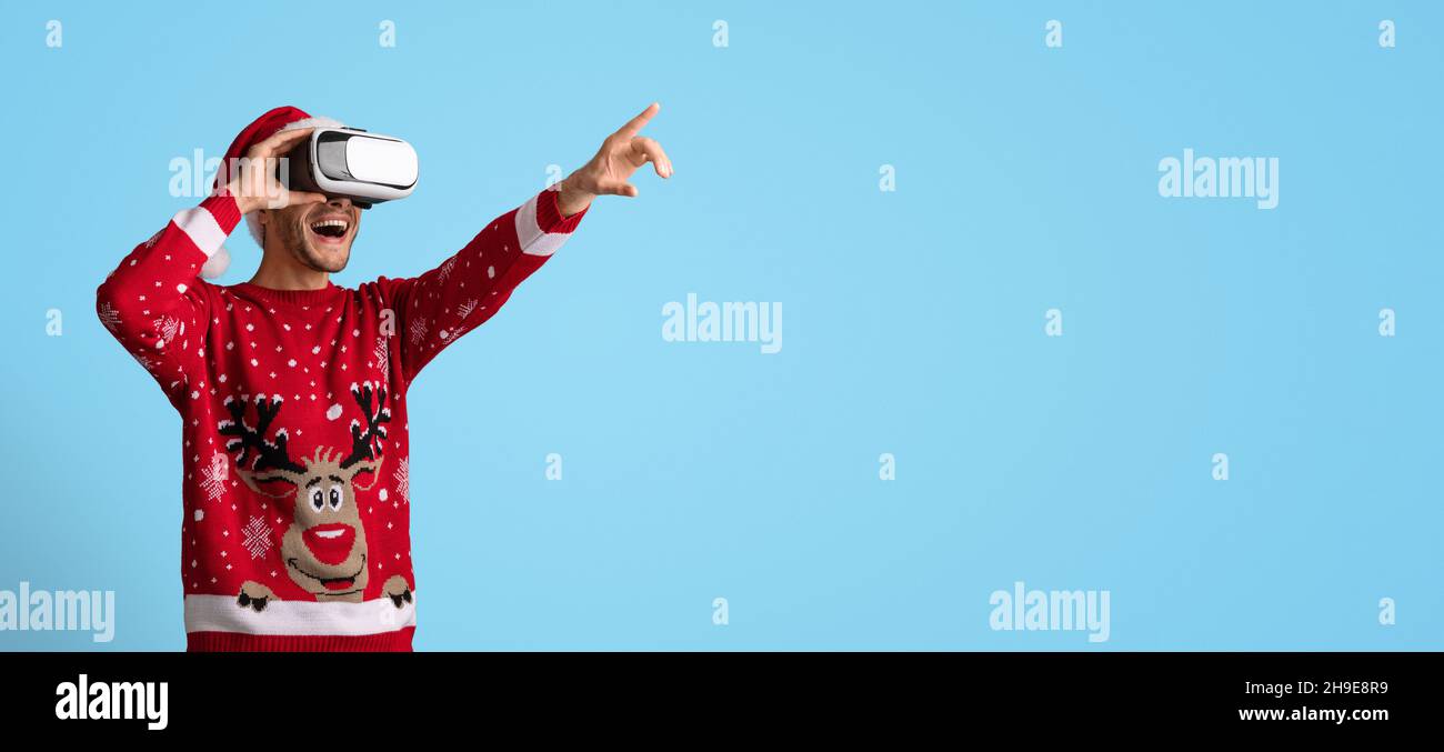 Virtuelle Party. Aufgeregt Mann In Vr-Brille Und Weihnachtspullover Zeigt Weg Stockfoto