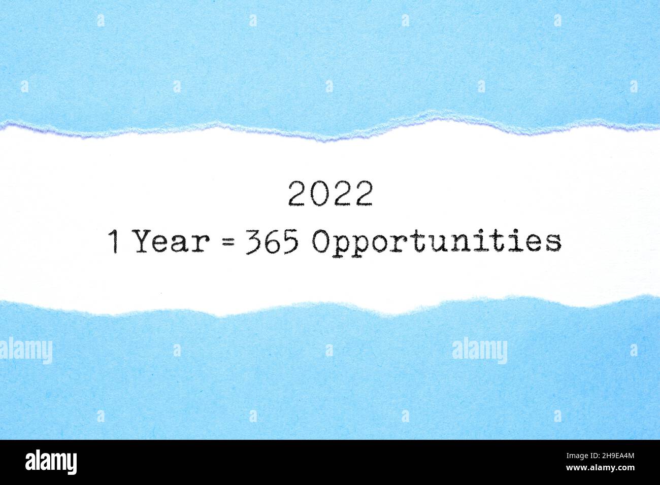 Inspirierende Nachricht 1 Jahr 2022 gleich 365 Gelegenheiten, die hinter zerrissenen blauen Papier erscheinen, das auf weißem Blatt getippt wurde. Stockfoto