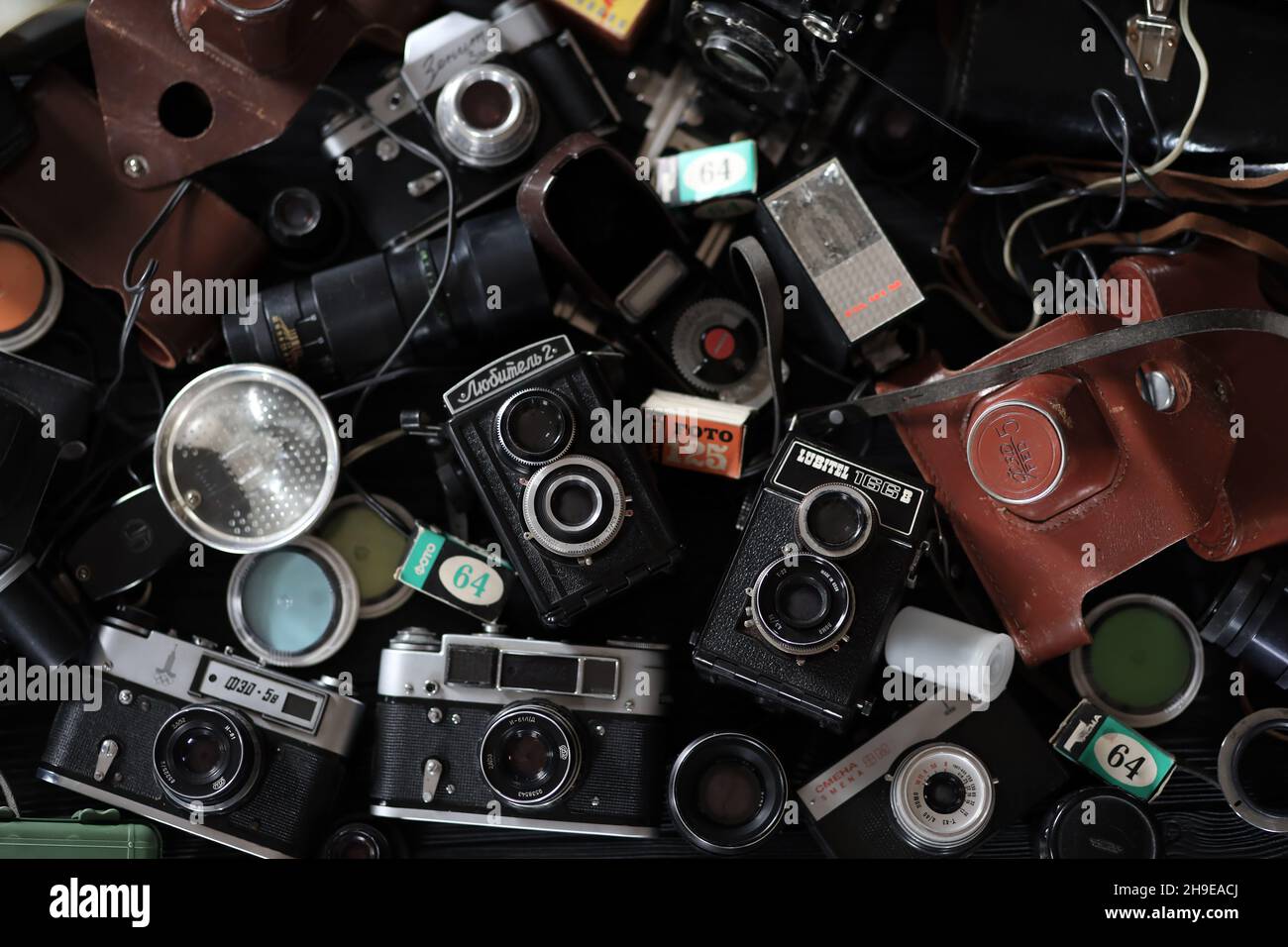 CHARKOV, UKRAINE - 27. APRIL 2021: Filmkameras und eine andere alte Retro-Fotoausrüstung auf schwarzem Holztisch in der Dunkelkammer des Fotografen. Foto Stockfoto