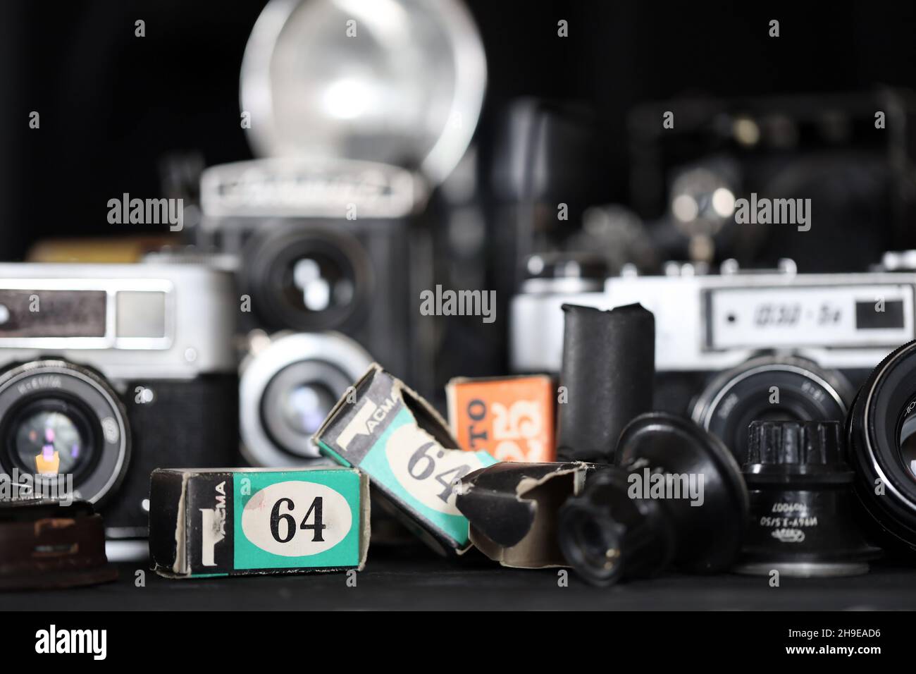 CHARKOV, UKRAINE - 27. APRIL 2021: Filmkameras und eine andere alte Retro-Fotoausrüstung auf schwarzem Holztisch in der Dunkelkammer des Fotografen. Foto Stockfoto