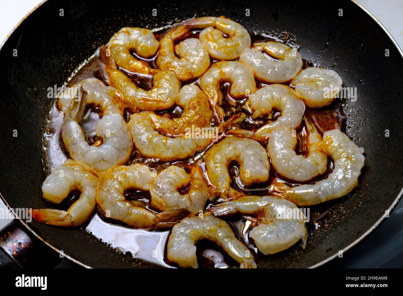 Kochen Sie würzige Tail-on-garnelen-Abendessen oder Vorspeise in der Pfanne auf dem Herd Stockfoto