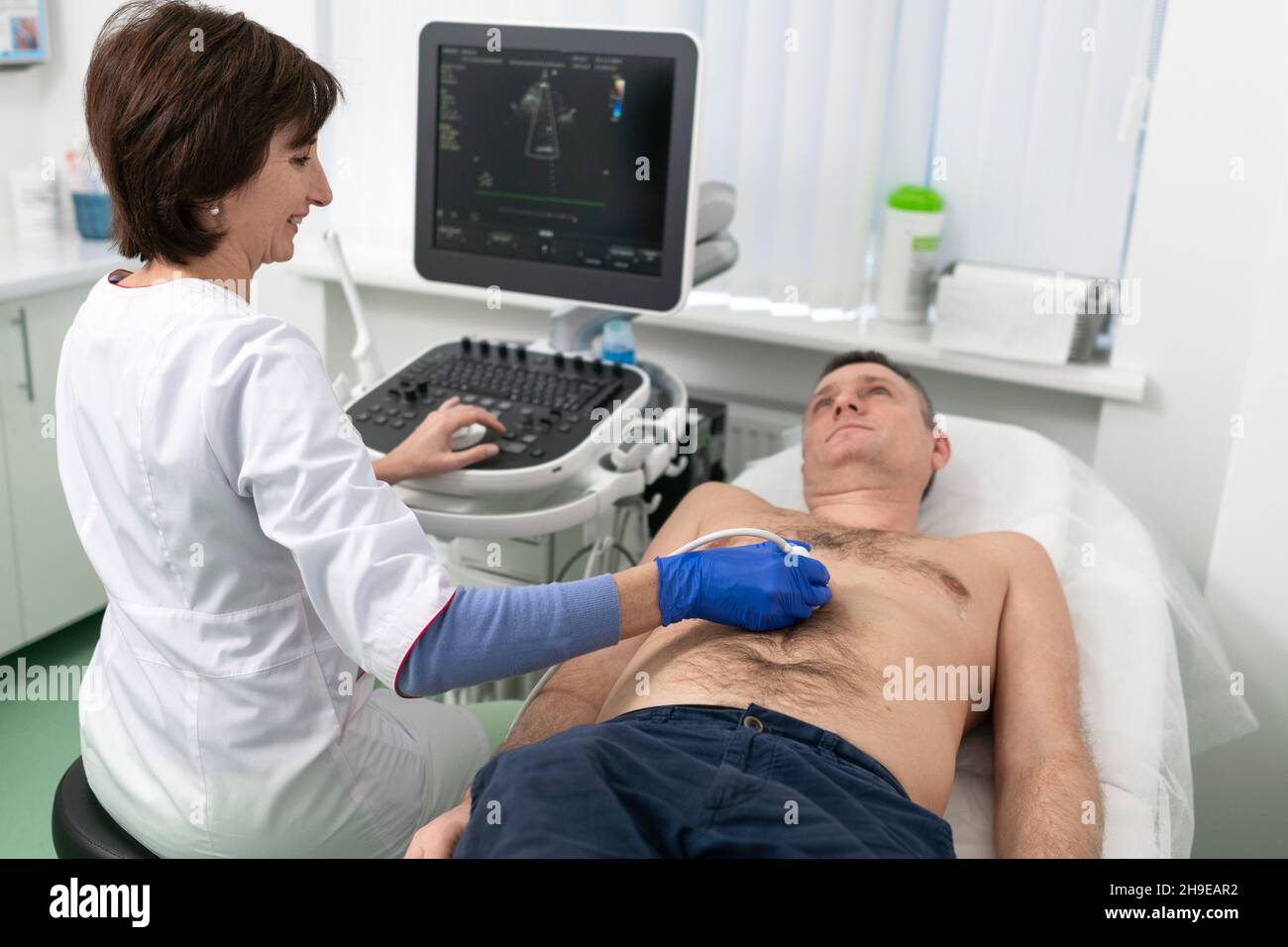 Ärztin macht Herzprüfung des Patienten Mann mit modernen Geräten in einer Kardiologie Klinik. Die Kardiologin schreit mit dem Herzen des Patienten Stockfoto