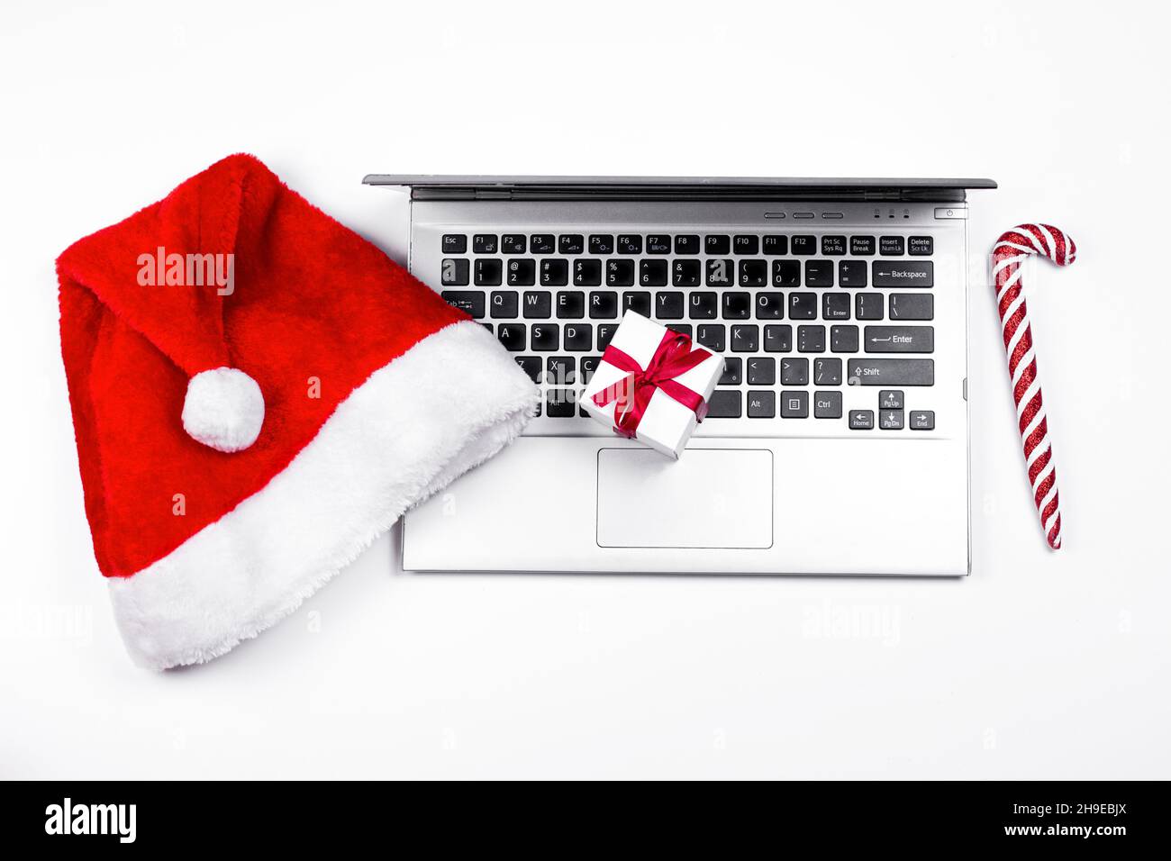 Weihnachtsmannhut und alter Laptop auf weißem Hintergrund. Weihnachtsurlaub und Neujahrsurlaub Konzept. Stockfoto