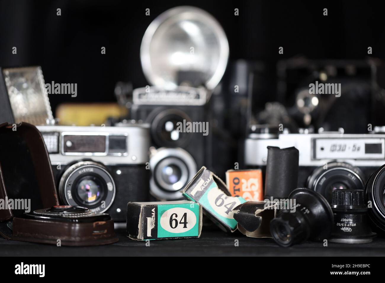 CHARKOV, UKRAINE - 27. APRIL 2021: Filmkameras und eine andere alte Retro-Fotoausrüstung auf schwarzem Holztisch in der Dunkelkammer des Fotografen. Foto Stockfoto