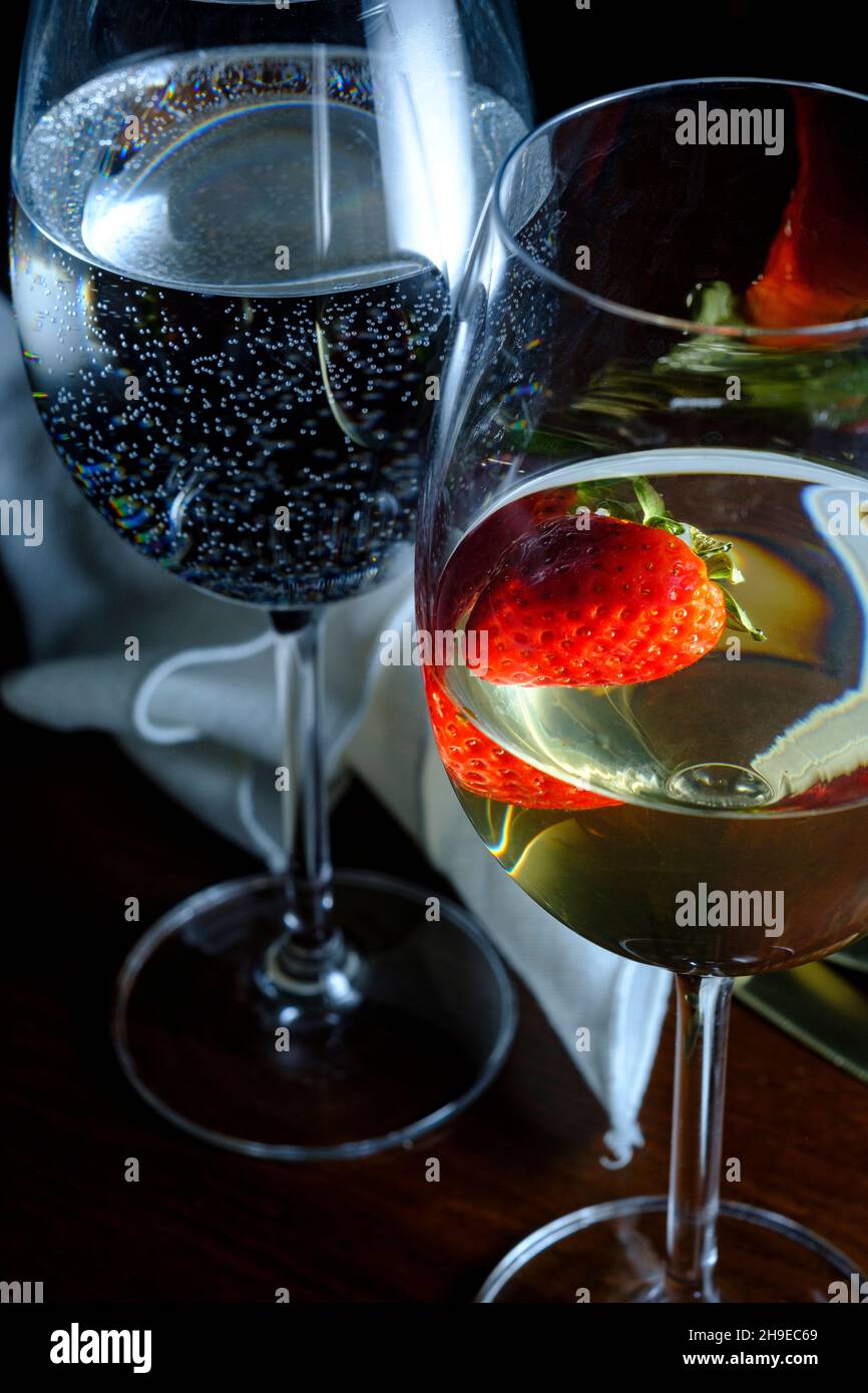 Romantisches Date in einem schicken Restaurant mit Pinot grigio Weißwein mit Erdbeere, die im Glas schwebt Stockfoto