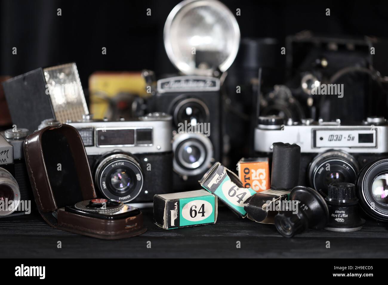 CHARKOV, UKRAINE - 27. APRIL 2021: Filmkameras und eine andere alte Retro-Fotoausrüstung auf schwarzem Holztisch in der Dunkelkammer des Fotografen. Foto Stockfoto