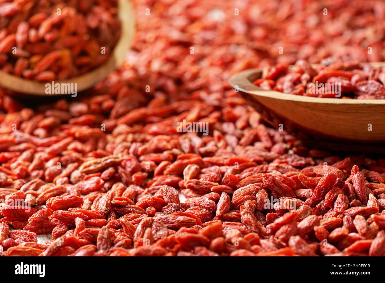 Trockene Goji-Beeren in kleinen Holzschüsseln, verteilt auf dem Schreibtisch unten Stockfoto