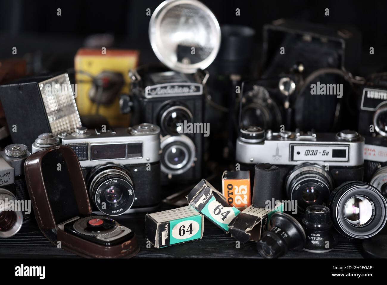 CHARKOV, UKRAINE - 27. APRIL 2021: Filmkameras und eine andere alte Retro-Fotoausrüstung auf schwarzem Holztisch in der Dunkelkammer des Fotografen. Foto Stockfoto