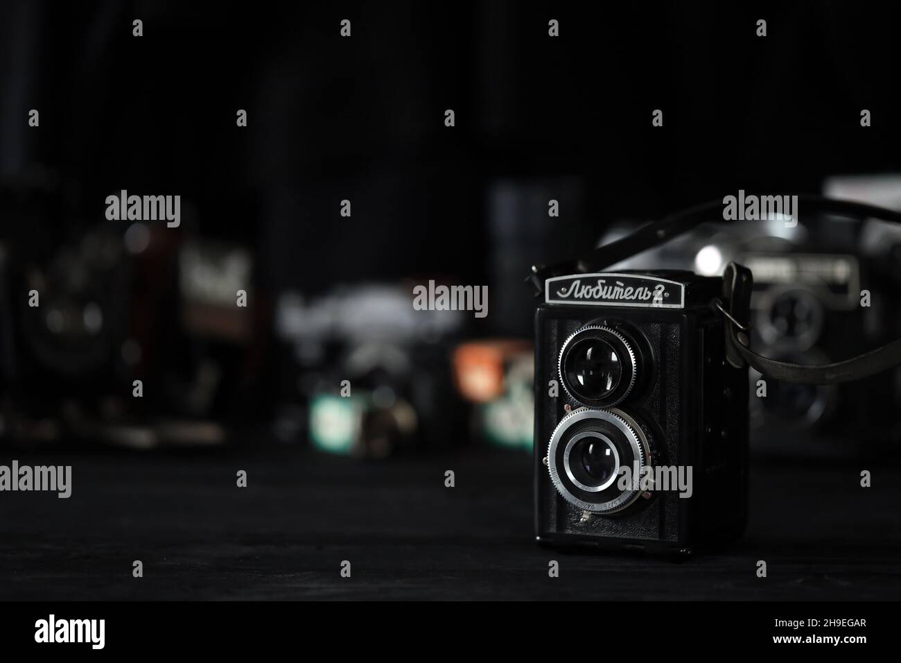 CHARKOV, UKRAINE - 27. APRIL 2021: Lubitel 166b und 2 Filmfotokamera und eine andere alte Retro-Fotoausrüstung auf schwarzem Holztisch in Fotograf da Stockfoto