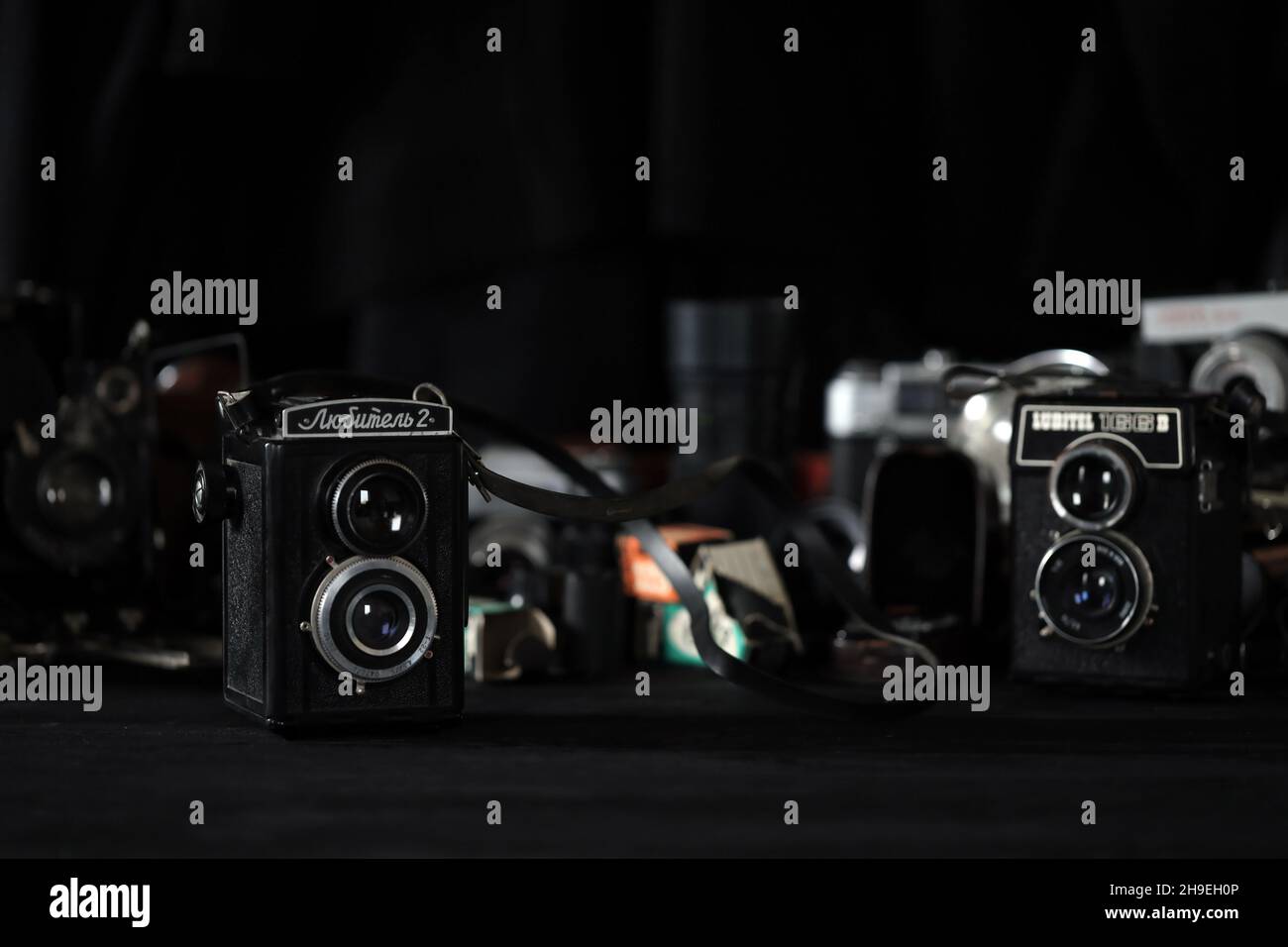CHARKOV, UKRAINE - 27. APRIL 2021: Lubitel 166b und 2 Filmfotokamera und eine andere alte Retro-Fotoausrüstung auf schwarzem Holztisch in Fotograf da Stockfoto