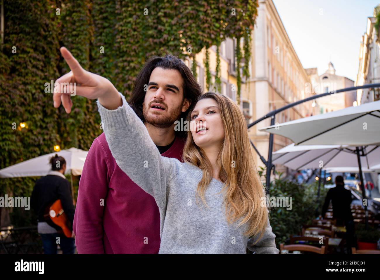 Schönes Paar, das nach Rom reist. Eine blonde Frau weist ihrem Freund den Weg. Junge Menschen schauen in die gleiche Richtung. Stockfoto