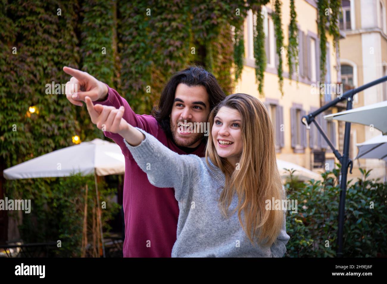 Schönes Paar, das nach Rom reist. Eine blonde Frau weist ihrem Freund den Weg. Junge Menschen schauen in die gleiche Richtung und lächeln. Stockfoto