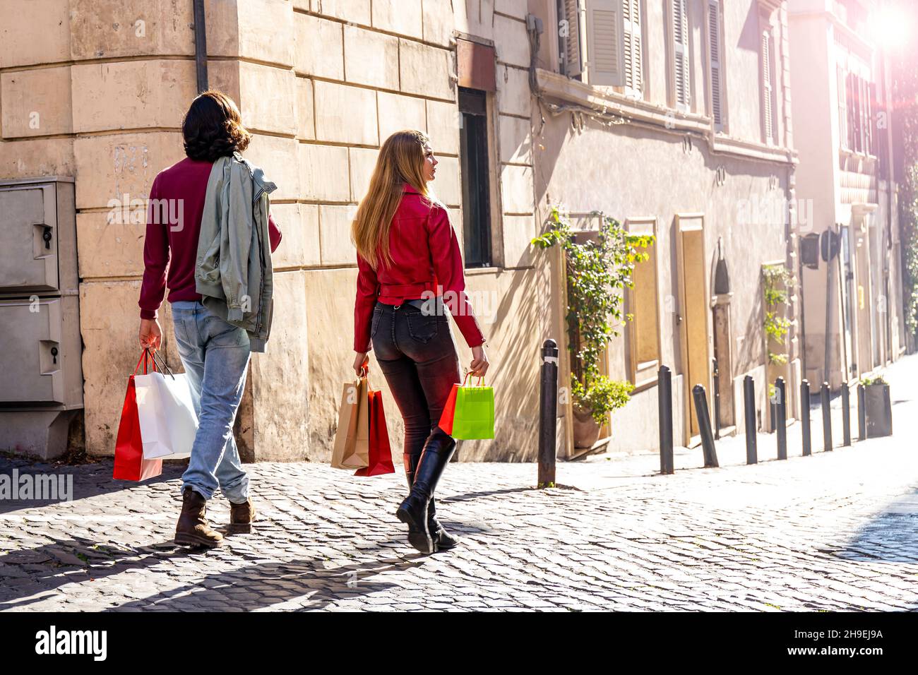 Schönes Paar, das nach Rom reist. Das junge Paar ging einkaufen und spaziert mit farbigen Taschen durch die Straßen des historischen Zentrums. Einkaufsbummel Stockfoto