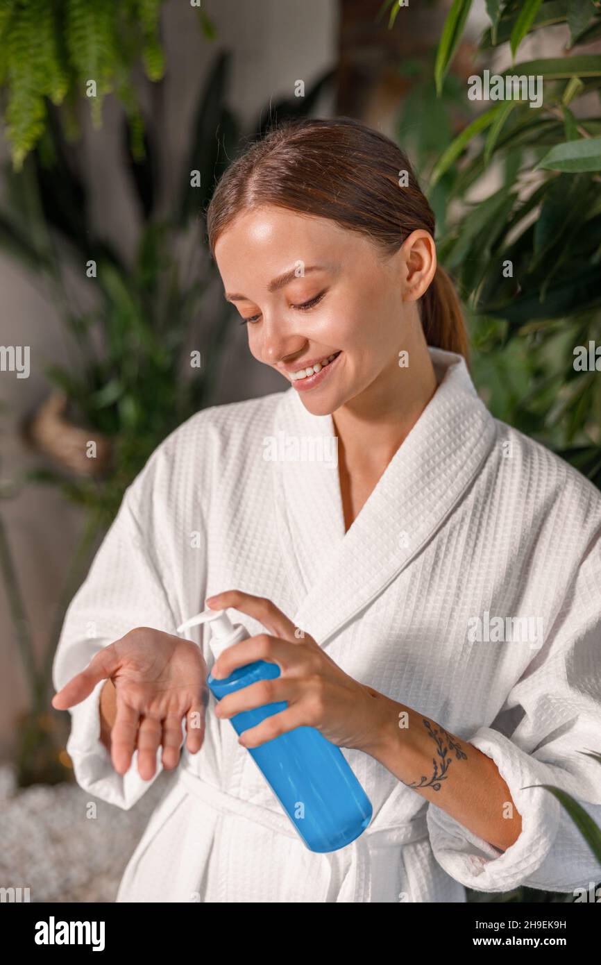 Junge schöne Frau hält eine Flasche mit Gel waschen, spezielle Behandlung für empfindliche Haut, während im Spa-Bad stehen Stockfoto