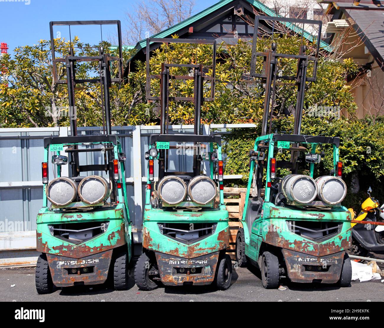 Kleine Gabelstapler in Türkis und Gelb, die vor einem Lagerhaus neben dem Tsukiji Fischmarkt in Tokio, Japan, geparkt sind. Stockfoto