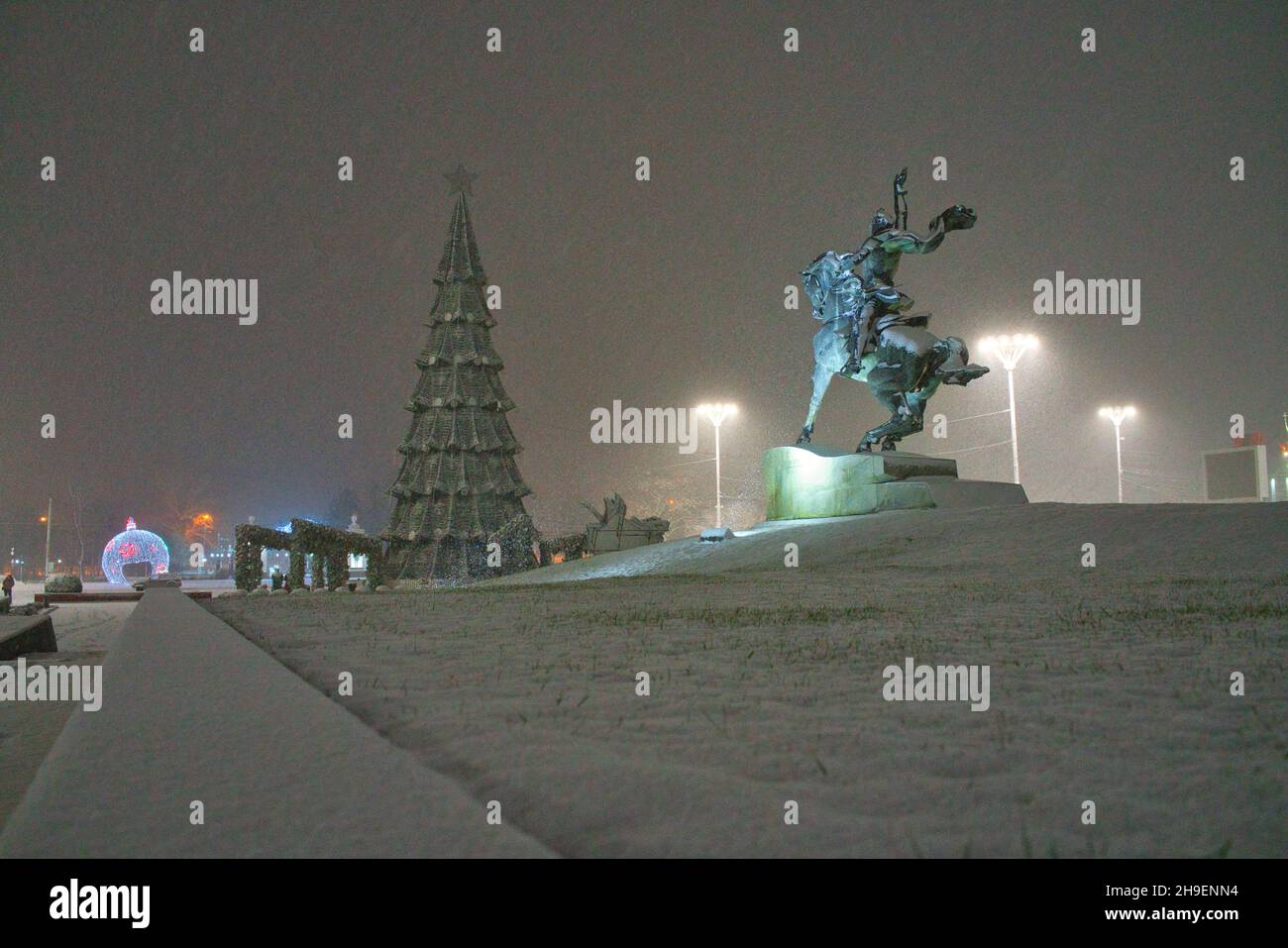 TIRASPOL, MOLDAWIEN - 06. Nov 2021: Nächtlicher Schneefall in der Nähe des Denkmals für General Suworow und eines Weihnachtsbaums in Tiraspol, Moldawien Stockfoto