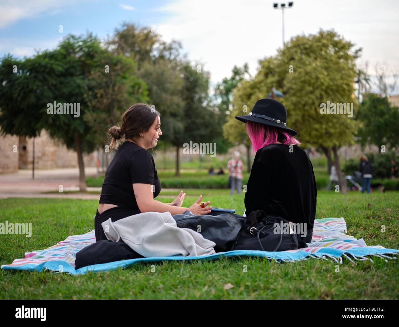 Horizontale Vollansicht von zwei Frauen, die auf einer Picknickdecke im Park sitzen Stockfoto
