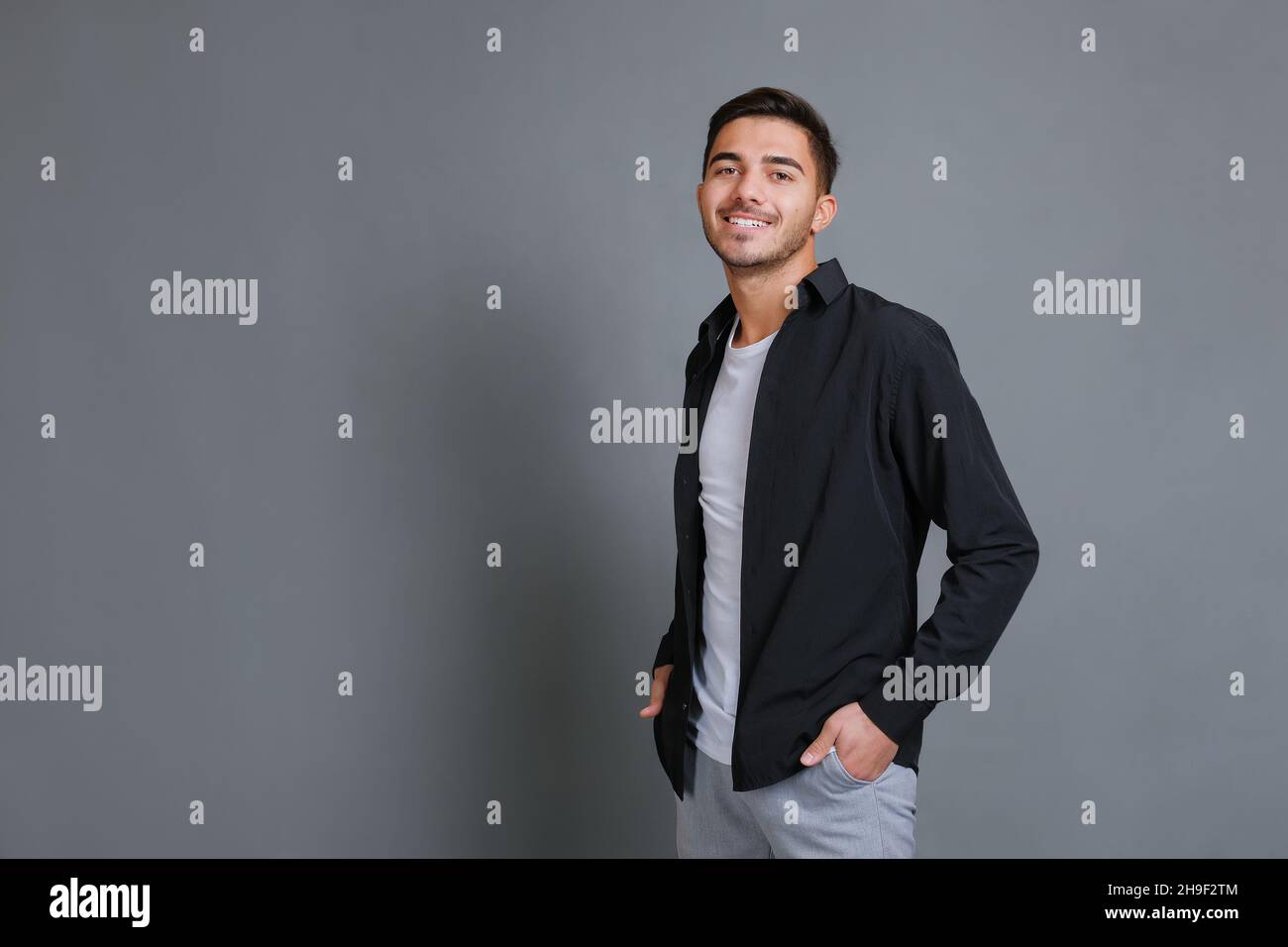 Porträt eines lächelnden, gutaussehenden und selbstbewussten jungen Geschäftsmannes in schwarzem Hemd Stockfoto