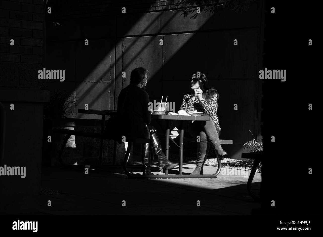 Schwarz-weißes Bild von zwei Frauen, die in einer Gasse zu Mittag essen. Stockfoto