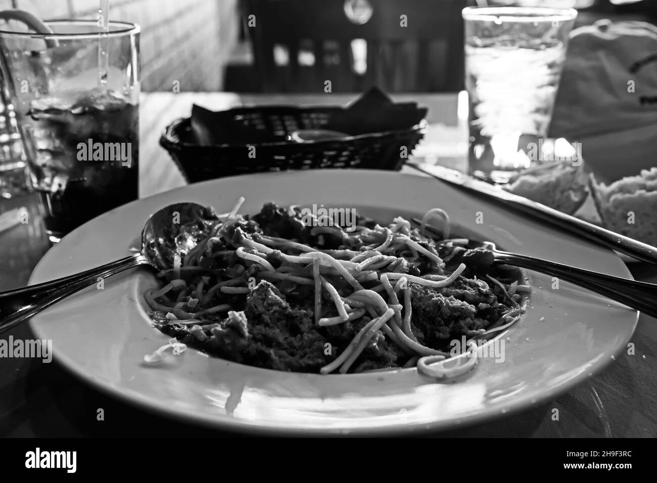 Schwarz-weißes Bild von Spaghetti auf einem weißen Teller. Mittags in einem italienischen Restaurant. Stockfoto