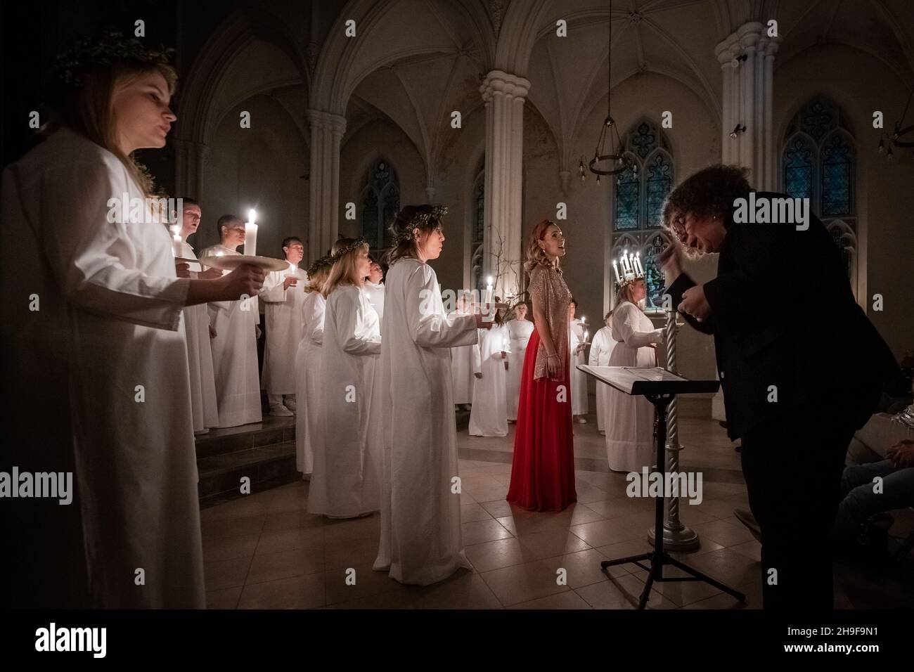 London, Großbritannien. 6th. Dezember 2021. Sarah Evander, die die Rolle der Lucia spielt, leitet die Prozession während des traditionellen skandinavischen Konzerts ‘Sankta Lucia’ des London Nordic Choir in der St. John’s Church unter der Leitung von Carina Einarson. Der Gottesdienst besteht aus einer Prozession von Chören bei Kerzenschein, die von einem Mädchen, Lucia, geführt wird, das eine Krone aus Kerzen und eine rote Schärpe um ihre Taille trägt. Kredit: Guy Corbishley/Alamy Live Nachrichten Stockfoto