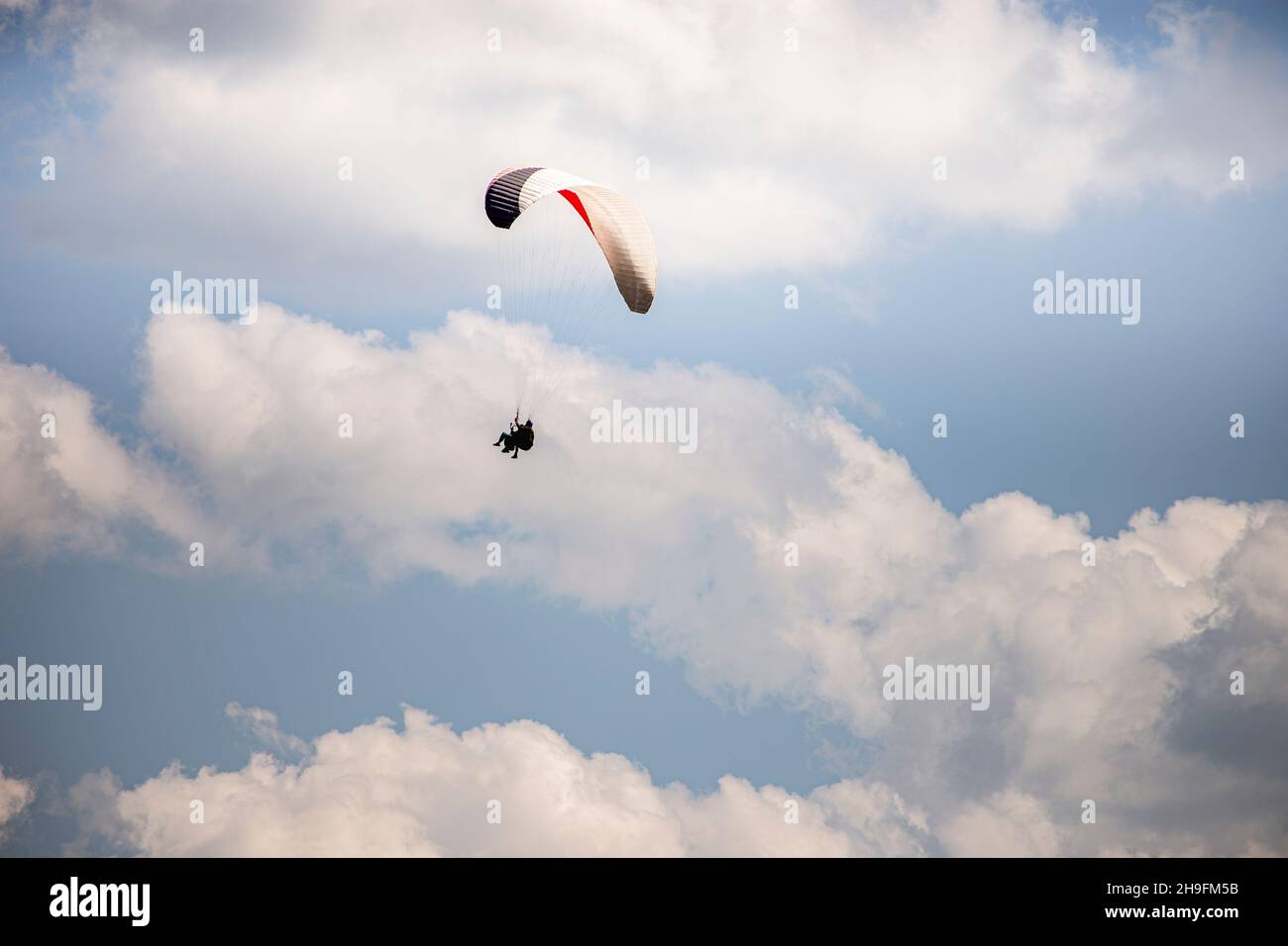 Gleitschirmfliegen mit einem Paar Instruktoren. Strahlend blauer Himmel mit schönen weißen, flauschigen Wolken. Freizeit mit aktiven Abenteuern. Tourismus in Georgien Stockfoto