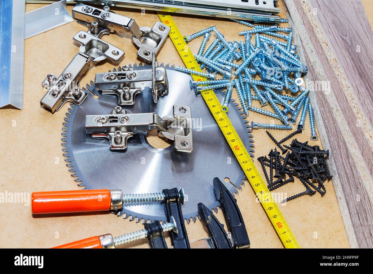 Schrauben, Bestätigungen für Möbel, Maßband, liegen auf dem Tisch. Möbelproduktion. Stockfoto