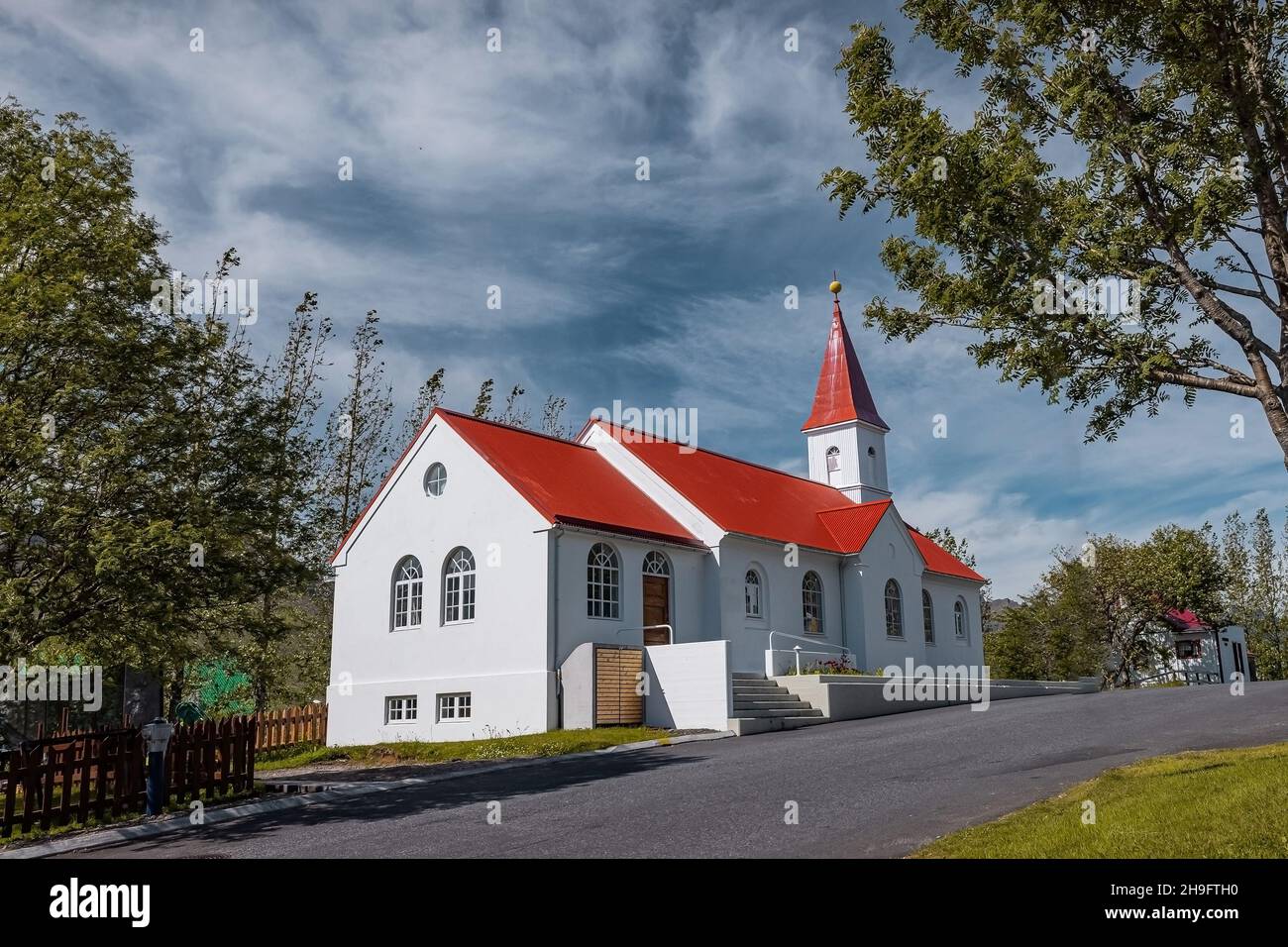 Schöne typische Kirche in Faskrudsfjordu oder Fáskrúðsfjörður auf Island. Weiße Wände und rotes Dach an einem sonnigen Tag in Island. Stockfoto