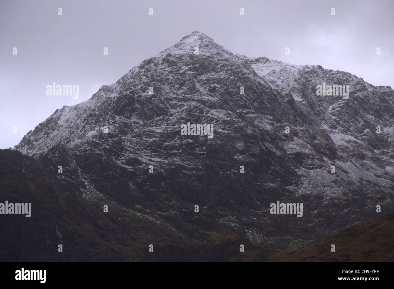 Winter im Snowdonia National Park (Eryri), Wales, Großbritannien. Schnee auf dem Gipfel des Snowdon (Yr Wyddfa), dem höchsten Berg in Wales, von der Bergarbeiterspur aus gesehen, als sich der Sturm Barra nähert. Es wird erwartet, dass starke Winde und Schnee das vereinigte königreich treffen werden. Der Berg liegt 1.085 Meter (3.560 Fuß) über dem Meeresspiegel und ist der höchste Punkt der Britischen Inseln außerhalb der schottischen Highlands. Stockfoto