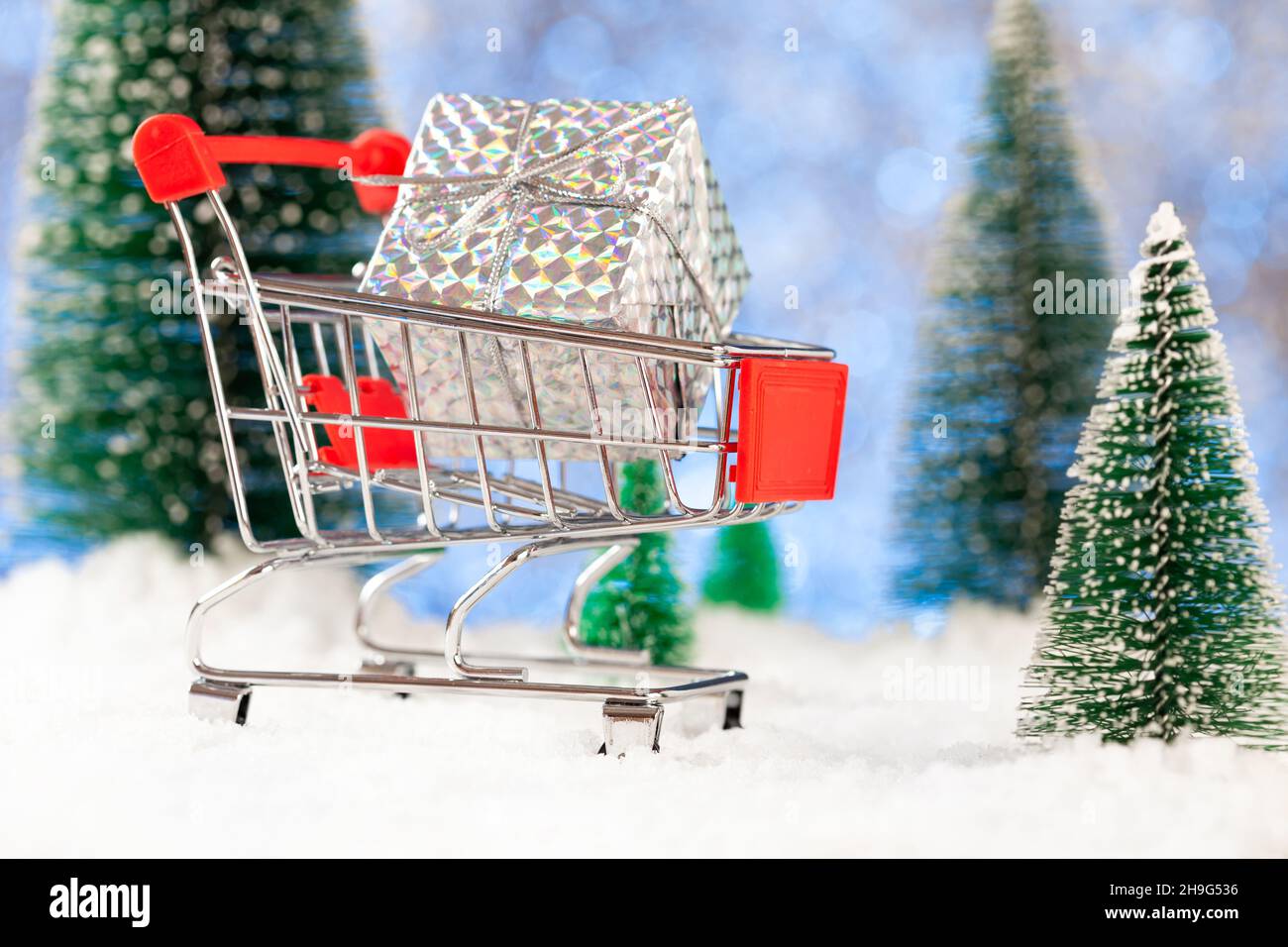 Neujahr und weihnachtseinkäufe für Geschenke, Supermarkt-Korb mit Geschenkbox auf Schnee, Konzept Stockfoto