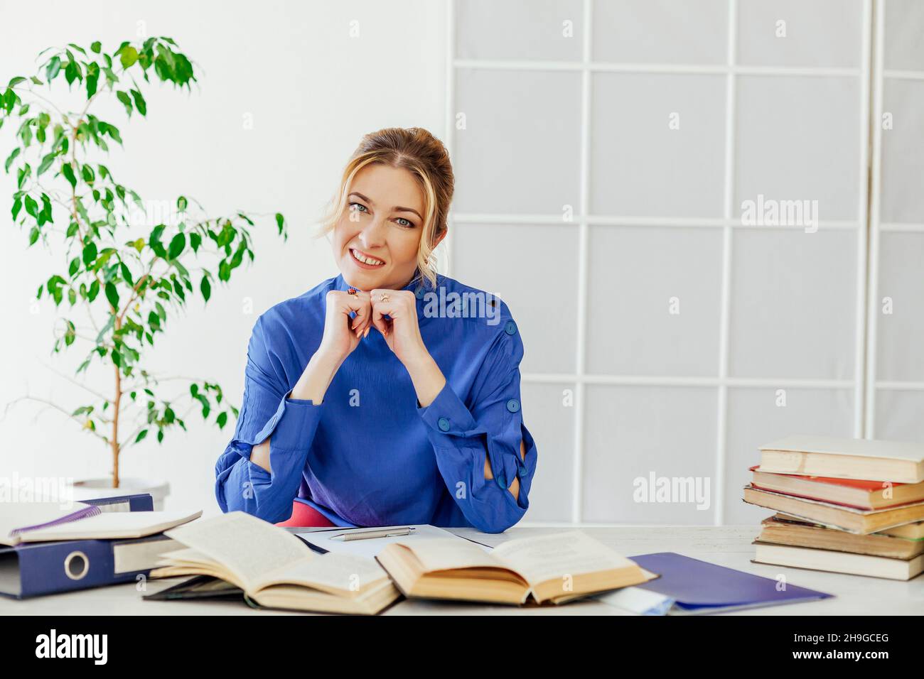 Eine Geschäftsfrau in einem Anzug sitzt an einem Schreibtisch mit Büchern Stockfoto