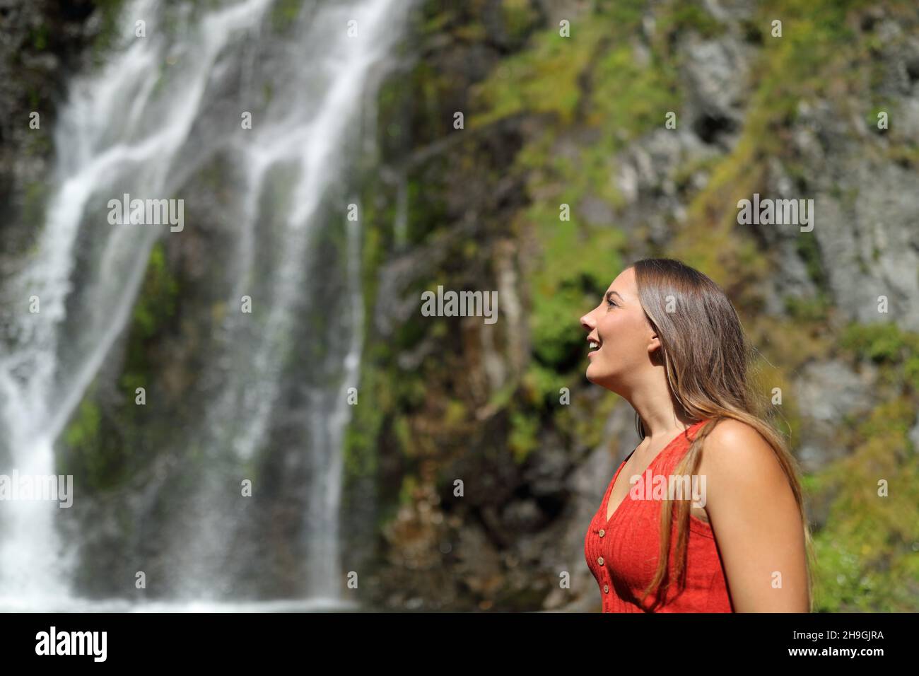 Seitenansicht Porträt einer staunenden Frau, die über einen Wasserfall nachdenkt Stockfoto