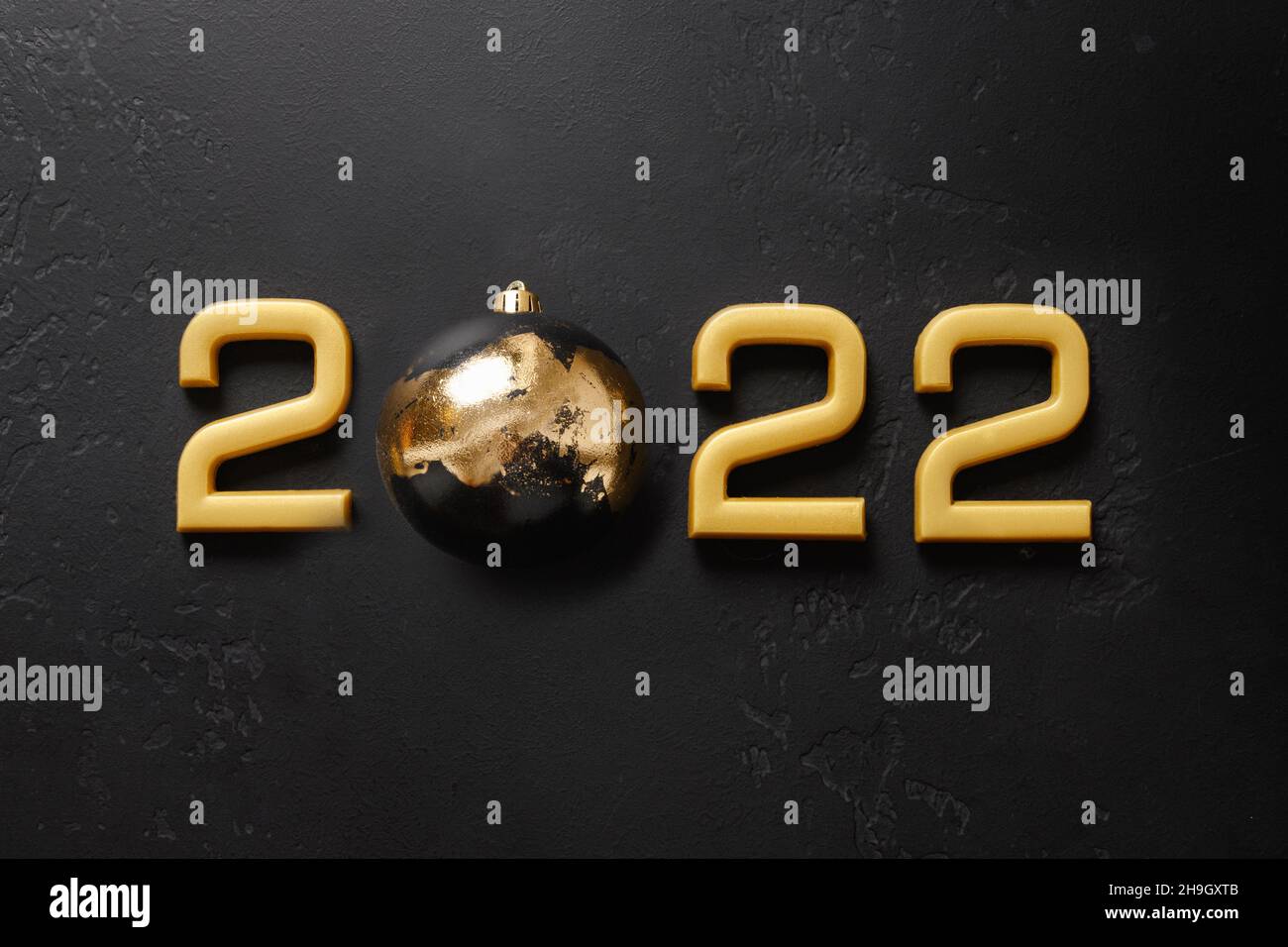 Frohes neues Jahr 2022 goldene Zahl mit Kugel verziert Luxus Metallic Potal isoliert auf schwarzem Nacht Hintergrund. Urlaubskonzept. Draufsicht, Kopierbereich. Stockfoto
