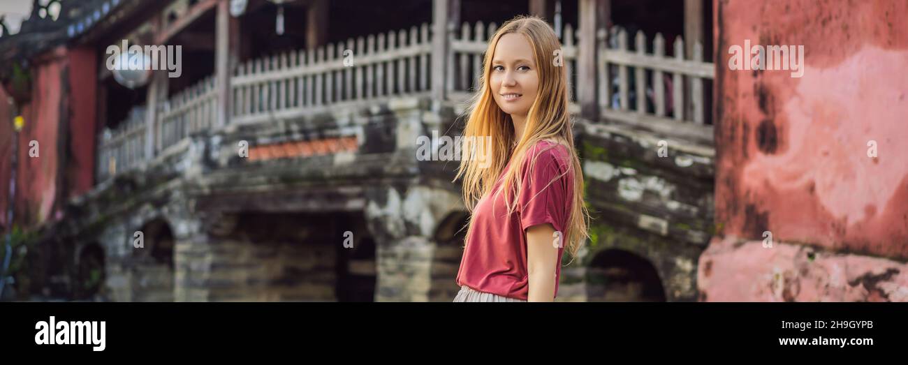 BANNER, LANGFORMATIGE Frau Tourist auf dem Hintergrund der schönen japanischen Brücke in Hoi an. Vietnam. Vietnam öffnet sich nach der Quarantäne wieder für Touristen Stockfoto