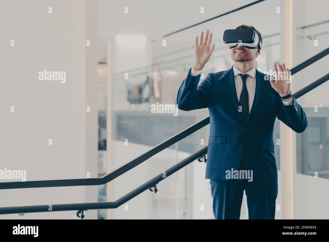 Beeindruckter Büroangestellter mit VR-Brille, der im Büro stand und die virtuelle Welt erkundeten Stockfoto