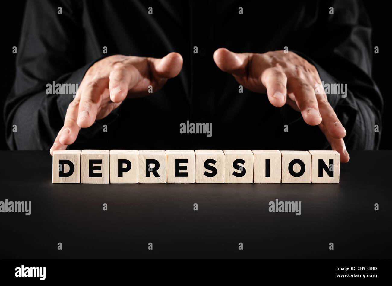 Männliche Hände über die Holzklötze mit dem Wort Depression. Stockfoto