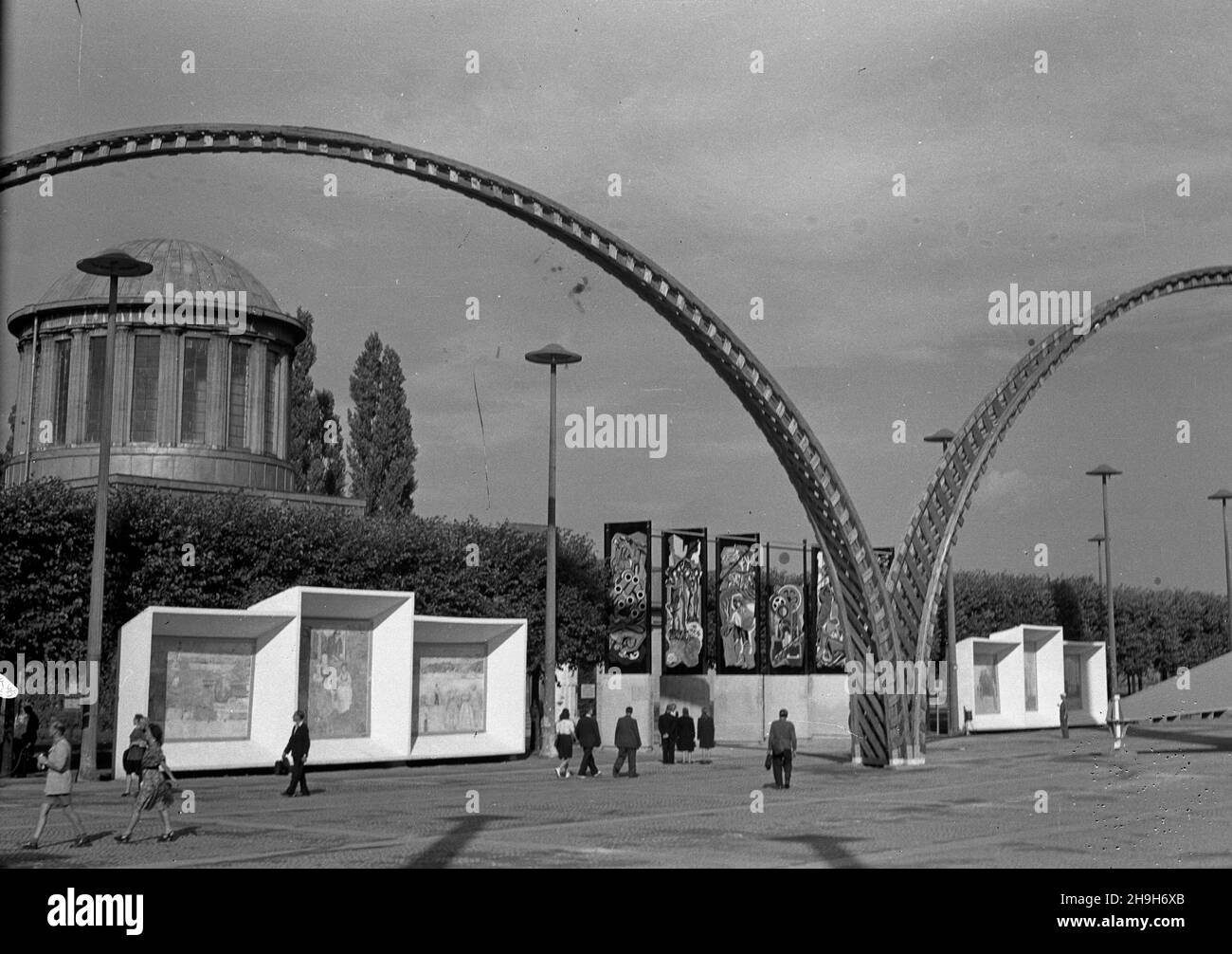 Wroc³aw, 1948-07. W dniach od 21 lipca do 31 paŸdziernika odbywa³a siê Wystawa Ziem Odzyskanych, która mia³a udowodniæ polskoœæ Œl¹ska. W kilkudziesiêciu pawilonach prezentowano dokonania Polski Ludowej. Przed wejœciem do Pawilonu Czterech Kopu³ ustawiono m.in. dwa tryptyki (autorstwa Jana Cybisa i Jerzego Wolffa) poœwiêcone odbudowie zniszczeñ wojennych i obecnoœci Polski nad Odr¹ i Nys¹ oraz malowane na szkle obrazy Henryka Sta¿ewskiego i Bohdana Urbanowicza. NZ. Tryptyki Cybisa i Wolffa (po Bokach) oraz obrazy Sta¿ewskiego i Urbanowicza (w œrodku); w tle Pawiilon Czterech Kopu³; na pierwszym Stockfoto