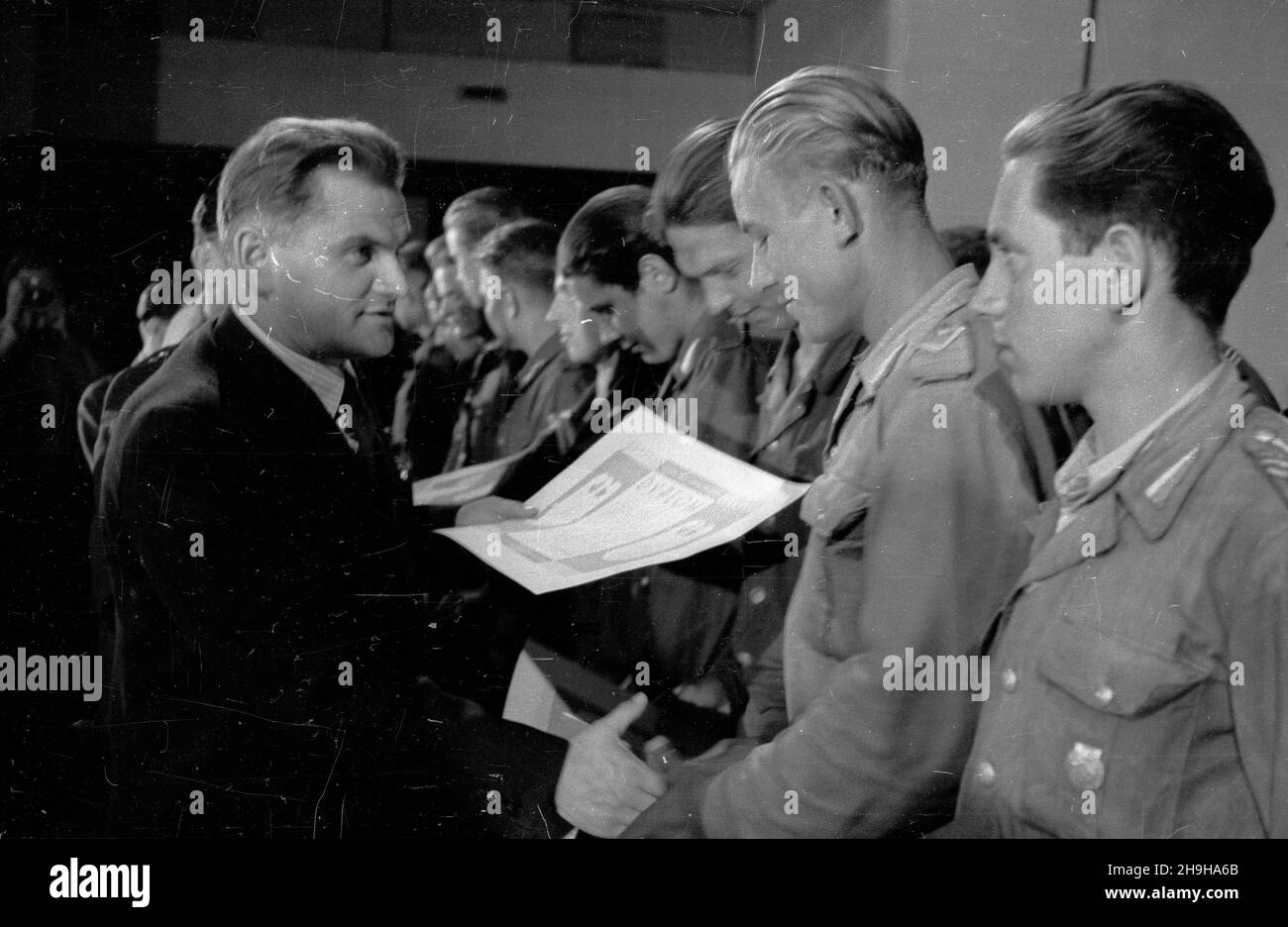 Warszawa, 1948-07-04. W gmachu Roma, przy ul. Nowogrodzkiej, odby³ siê i Krajowy Ogólnopolski Zlot Przodowników pracy Brygad M³odzie¿owych Powszechnej Organizacji S³u¿BA Polsce. Cz³onkom wyró¿nionych brygad wrêczono nagrotty. NZ. minister pracy i opieki spo³ecznej Kazimierz Rusinek (L) wrêcza junakom honorowe dyplomy. pw PAP Warschau, 4. Juli 1948. Die landesweite Kundgebung von 1st junger Arbeiterbanden und des Dienstes an den Arbeitskräften Polens fand im Roma-Theater in der Nowogrodzka-Straße statt. Auszeichnungen und Ehrendiplome wurden an die Mitglieder der besten Banden übergeben. Im Bild: Arbeit und Soziales Welfa Stockfoto