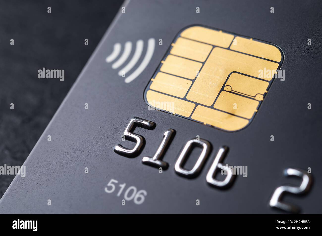 Schwarze Kreditkarte mit Chip und kontaktloser Bezahltechnologie Makro. Bankkarte für die Bezahlung von Waren und Dienstleistungen. Nahaufnahme der Debitkarte aus Kunststoff. Stockfoto