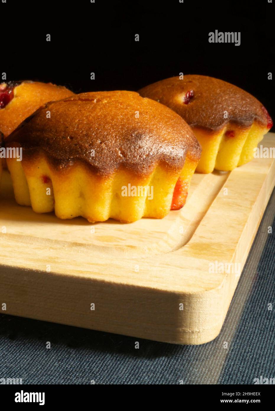 Die kleinen Obstkuchen mit Holzbrett auf Glastisch.Süß Backen auf schwarzem Hintergrund Stockfoto