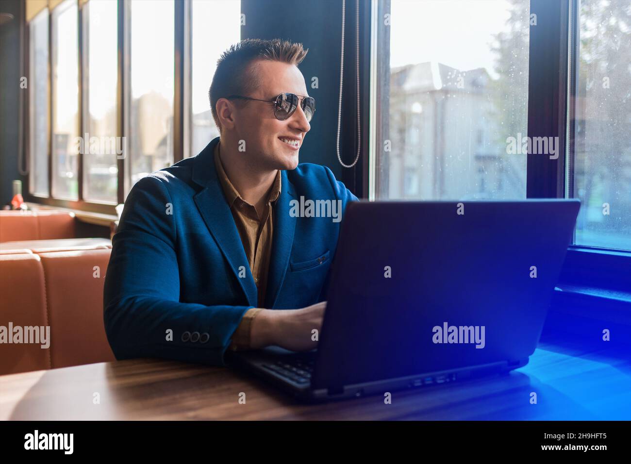 Ein Geschäftsmann glücklich lächelnden Geschäftsmann ein stilvolles Porträt des kaukasischen Aussehen in einer Jacke und Hemd, Sonnenbrille funktioniert in einem Laptop oder Computer, s Stockfoto