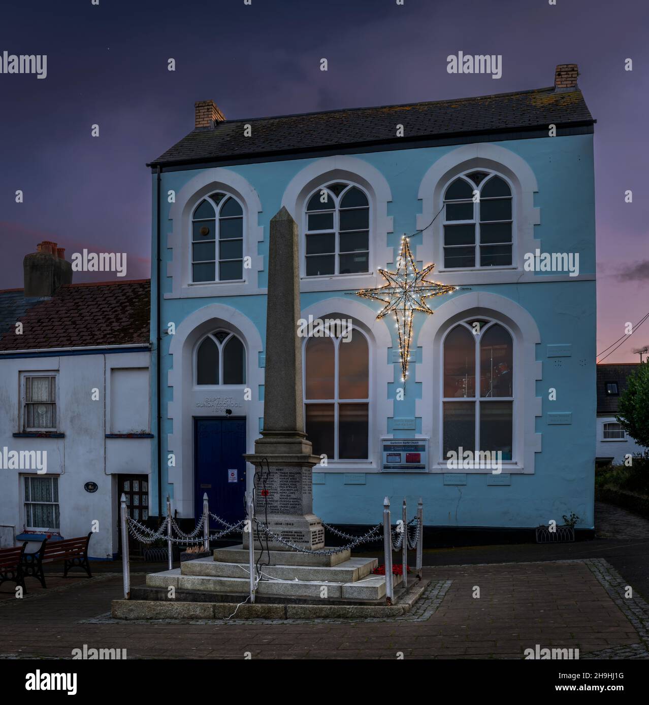 Die Appledore Baptist Church, die mit einem Weihnachtsstern verziert ist, steht neben dem war Memorial am Quay. Stockfoto