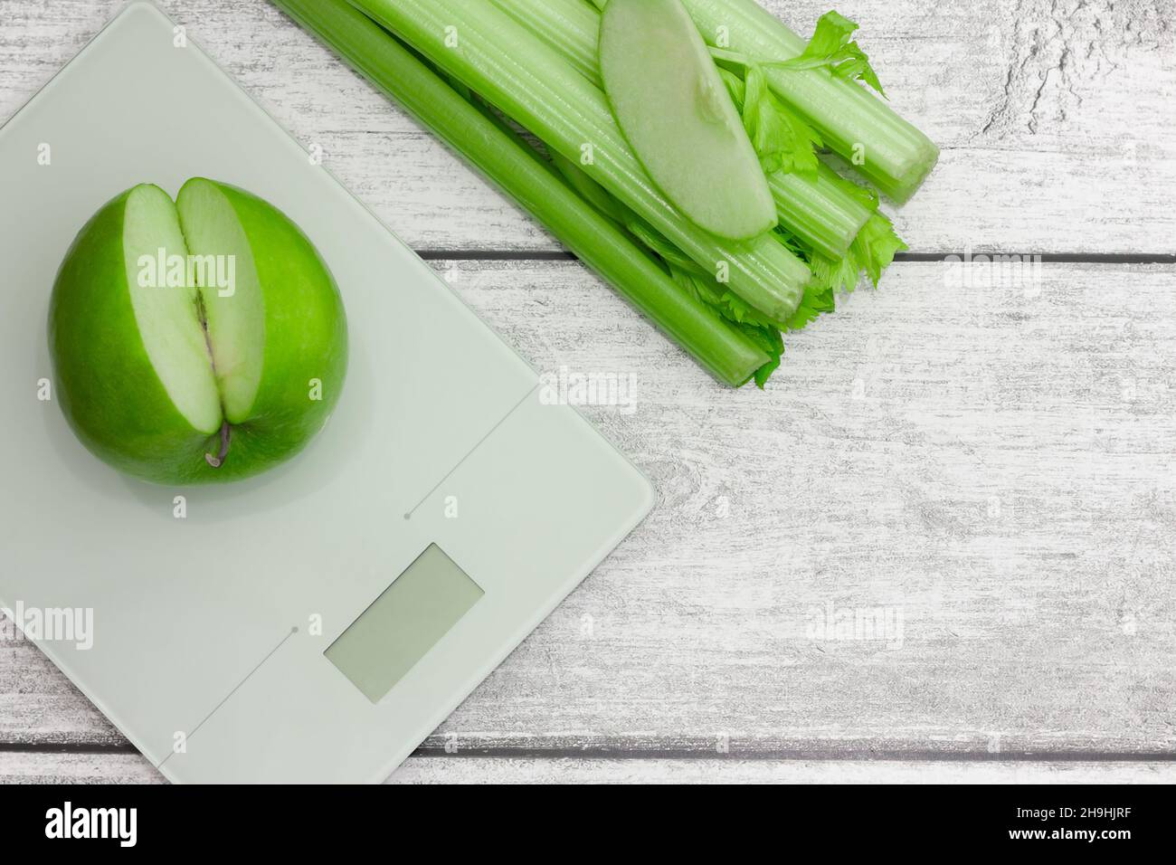 Grüner Apfel mit Sellerie wog auf einer Skala tolles Design für jeden Zweck. Vegetarische Gerichte. Frische, gesunde Lebensmittel. Holzhintergrund. Stockfoto