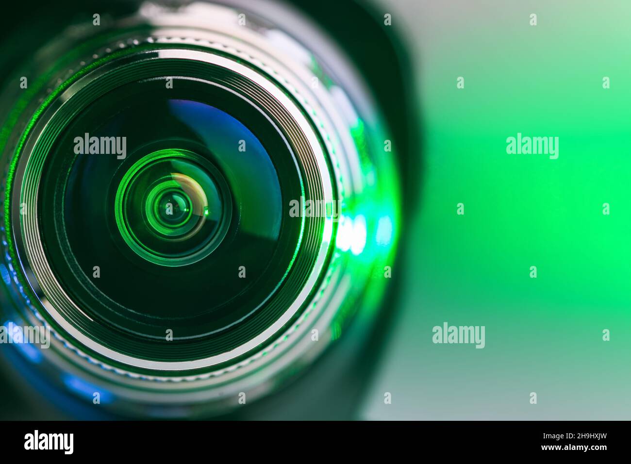 Das Kameraobjektiv und die grüne Hintergrundbeleuchtung. Grüne Kamera Nahaufnahme des Objektivs. Horizontales Foto Stockfoto