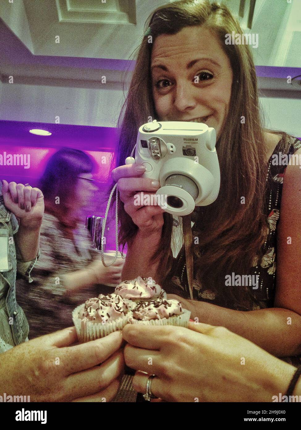 Eine Frau lächelt, als sie ein Foto von Cup Cakes auf der Brit Mums Konferenz 2013 macht (Teil einer Serie von Bildern, die Richard Grey, Gewinner des Terry O'Neill Awards für Mobilgeräte, auf dem iPhone aufgenommen und verarbeitet hat) Stockfoto