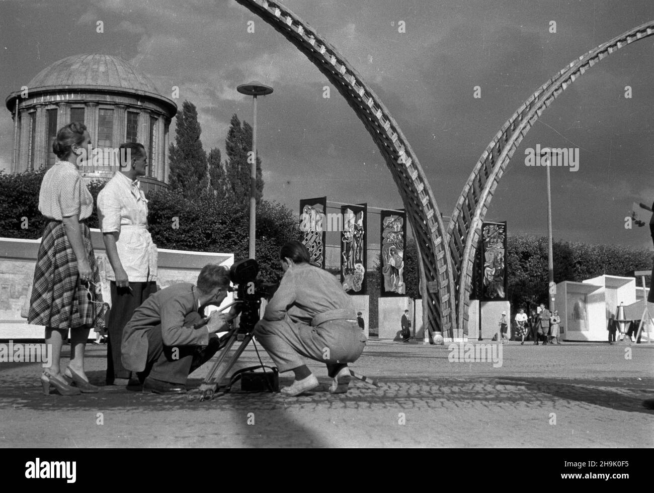 Wroc³aw, 1948-08. Wystawa Ziem Odzyskanych (21,07-31.10.1948). W sierpniu 1948 ekipa filmowa realizowa³a na terenie WZO propagandowy Film dokumentalny pt. Wystawa Ziem Odzyskanych. Realizatorem filmu by³a Jadwiga Pluciñska, ein Autorem zdjêæ Bogus³aw Lambach. NZ. Ekipa filmowa podczas zdjêæ na dziedziñcu wystawy, m.in.: Jadwiga Pluciñska (L) i Bogus³aw Lambach (za kamer¹, 2P); w g³êbi: Pawilon Czterech Kopu³, drewniane ³uki i dzie³a malarzy polskich, obrazy malowane na szkle i tryptyki. mta PAP Dok³adny dzieñ wydarzenia nieustalony. Breslau, 1948. August. Die Ausstellung der wiedergewonnenen Terri Stockfoto