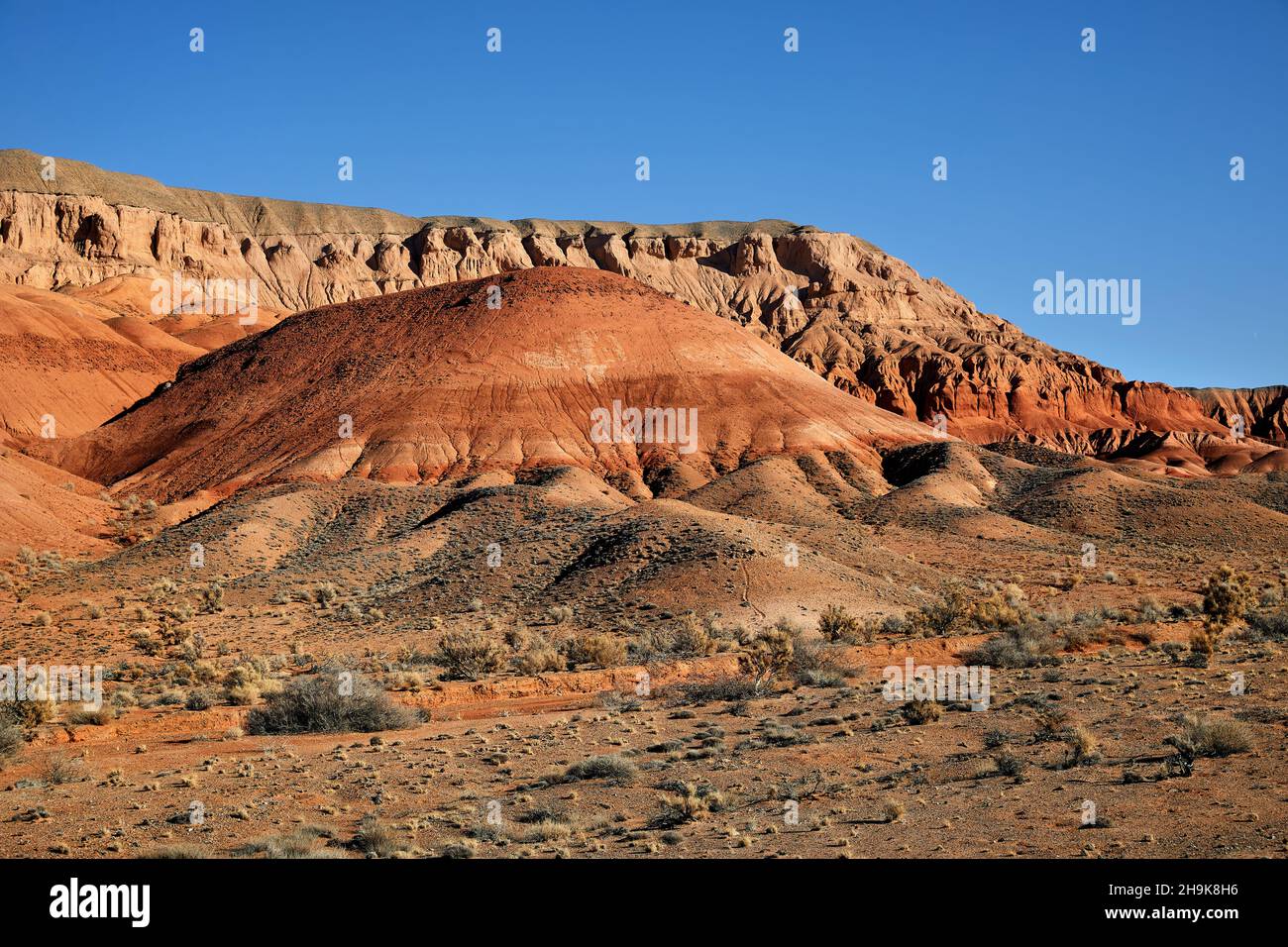 Landschaft aus roten Bergen in der Wüste, umgeben von verschneiten Bergen im Süden Kasachstans Stockfoto