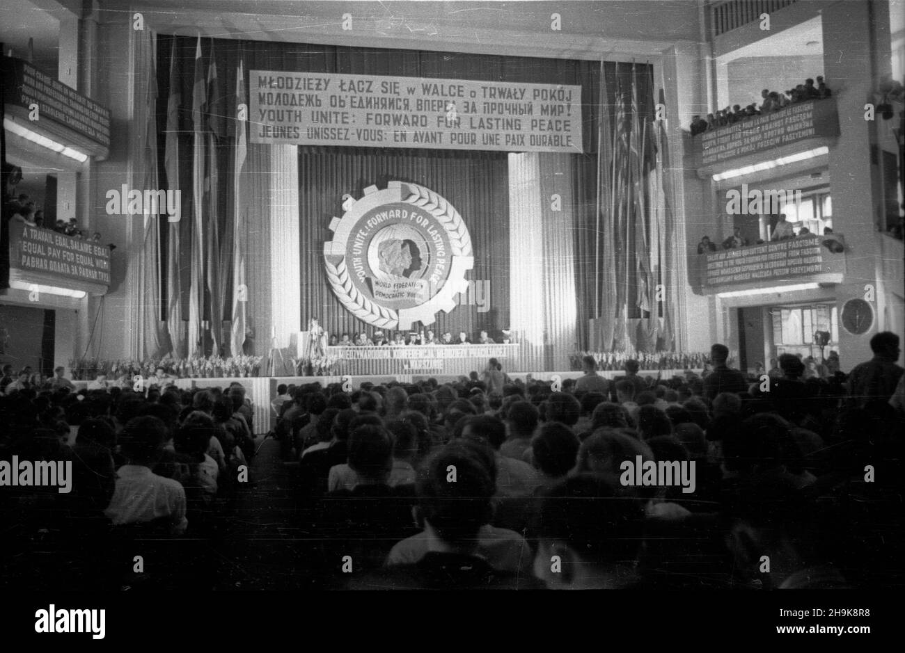 Warszawa, 1948-08-08. W Miêdzynarodowej Conferencji M³odzie¿y Pracuj¹cej trwaj¹cej do 14 sierpnia, wziê³o udzia³ kilka tysiêcy osób, w tym 500 goœci z zagranicy reprezentuj¹cych 46 pañstw. NZ. sala obrad i stó³ prezydialny, nad którym wywieszono, napisane w kilku jêzykach, g³ówne has³o konferencji: M³odzie¿y, ³¹cz siê w walce o trwa³y pokój. pw PAP Warschau, 8. August 1948. Die Internationale Konferenz der arbeitenden Jugend fand vom 8. Bis 14. August statt. Mehrere tausend Menschen nahmen an der Veranstaltung Teil, darunter 500 ausländische Gäste aus 46 Ländern. Im Bild: Der Präsidiumstisch mit den Konferenztischen Stockfoto