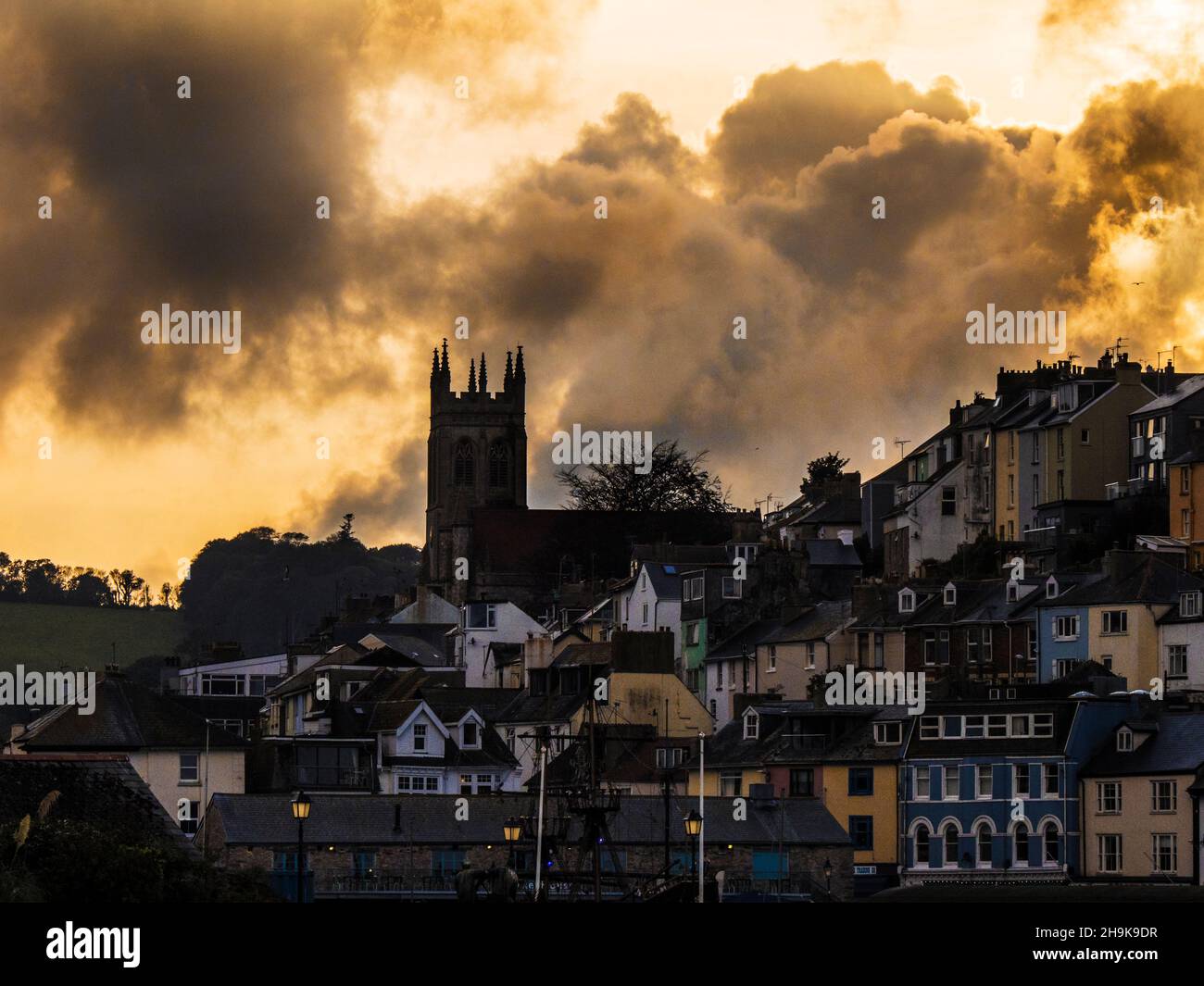 Ein dramatischer stürmischer Sonnenuntergang über der Allerheiligen-Kirche in Brixham, Devon. Stockfoto
